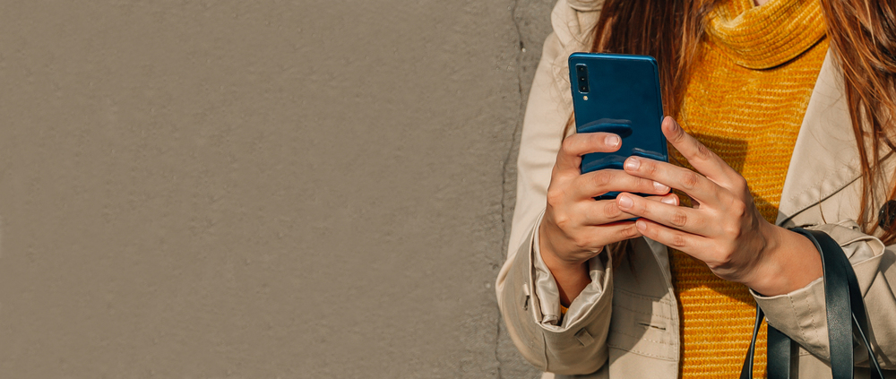 influencer 2026 jak oznaczać wspóøprace, urban girl using the phone or smart phone with wall background